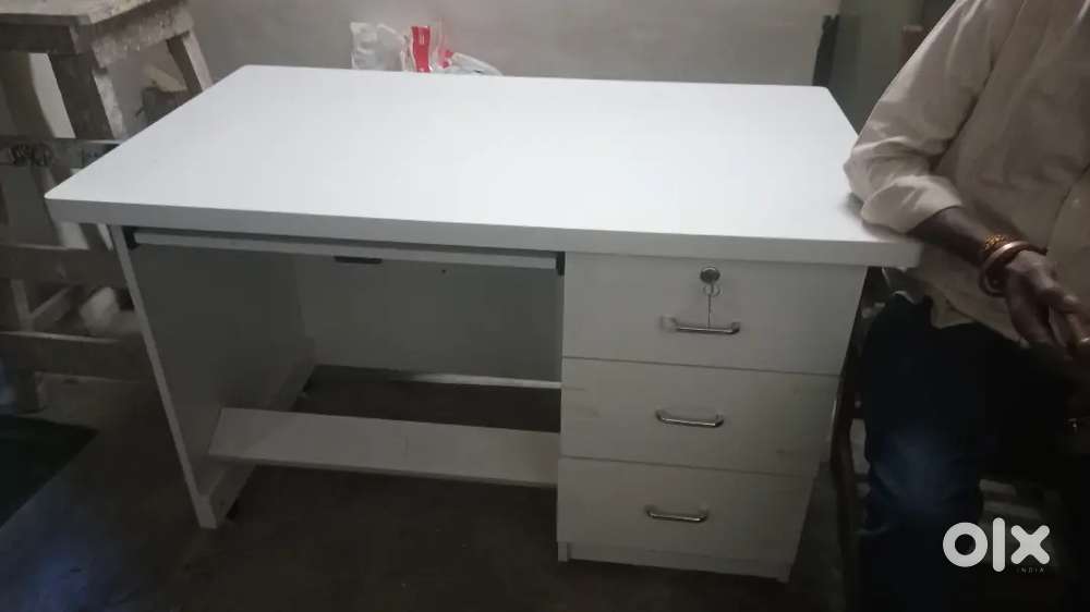 This is a white computer table with an open shelf and two drawers