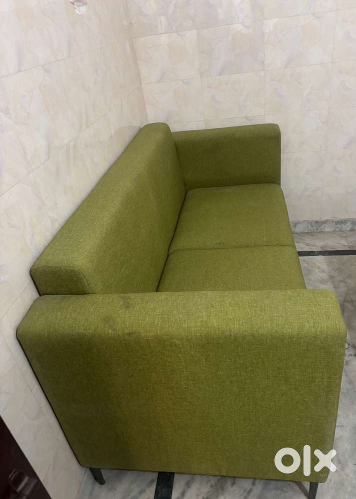 This is a green fabric two-seater sofa