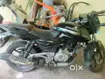 The image shows a black Bajaj Pulsar 180, a sports motorcycle model