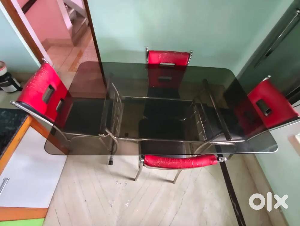 Steel dining table having 0.5 inches glass top with 4 chairs.