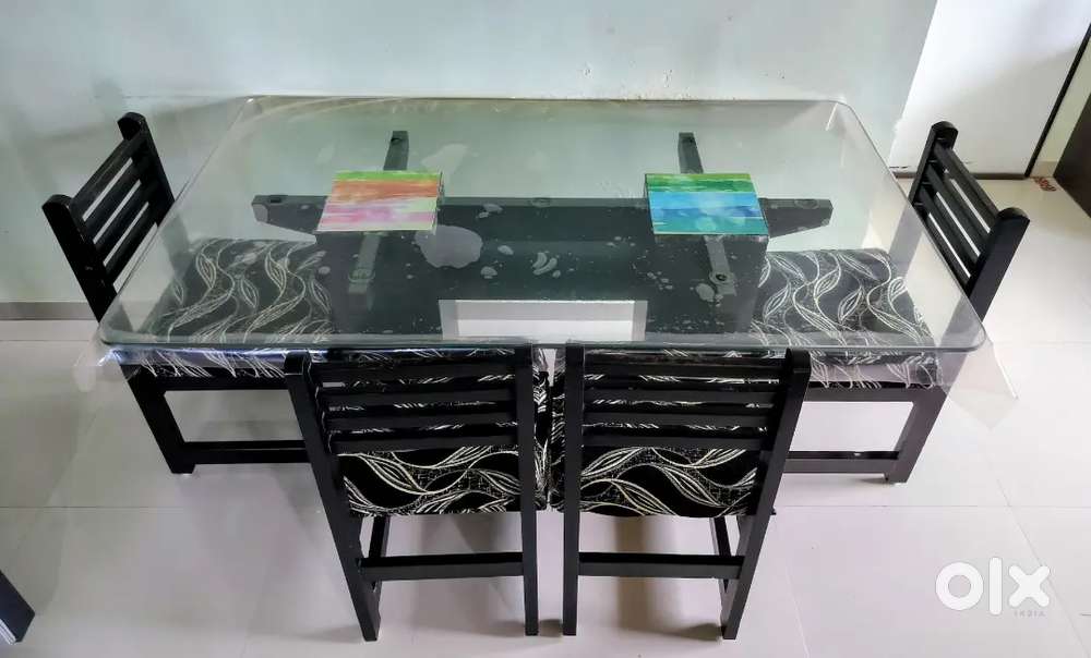 Glass Dining Table With 4 Wooden Chairs. Capacity of 6 persons.