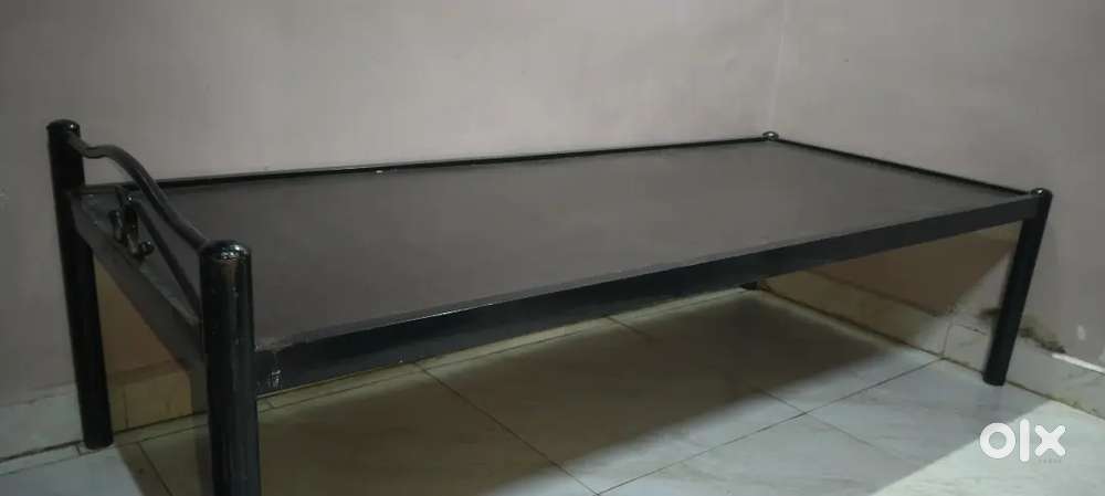 An iron frame bed with plywood.