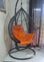 Brown swing chair with stand and orange cushion