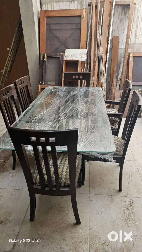 Dining table six seater.Made of teak wood with glass top.