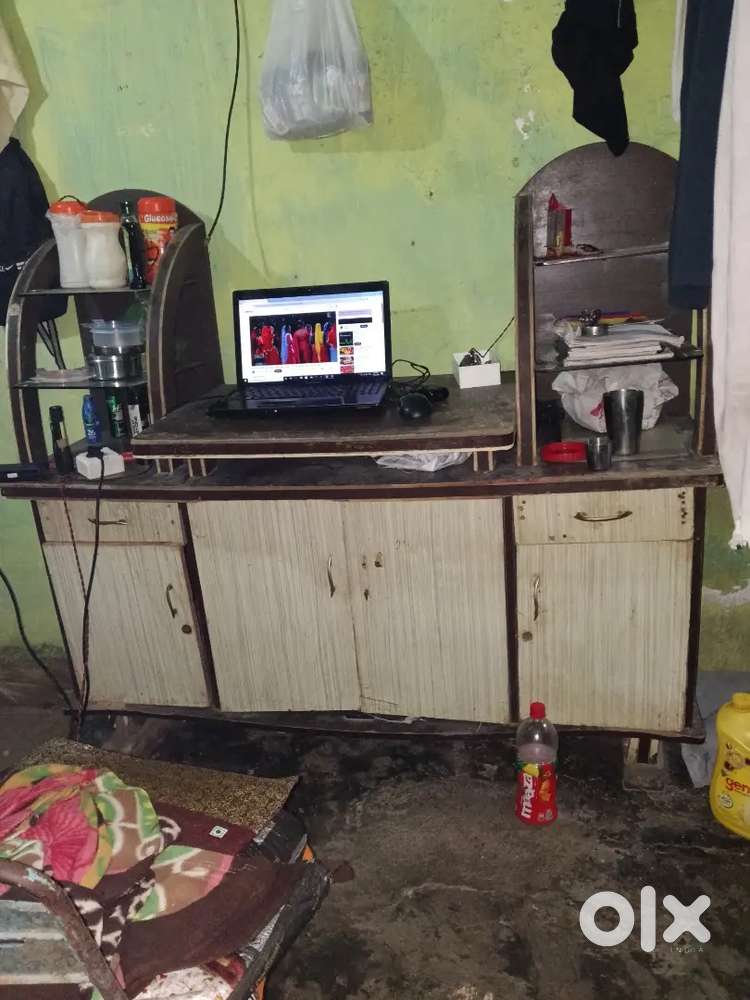 The image shows a laptop on a wooden desk, a power strip with a plug,
