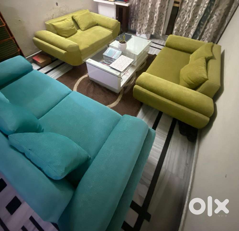 A seven seater sofa paired with a glass table, a mat and 7 cushions.