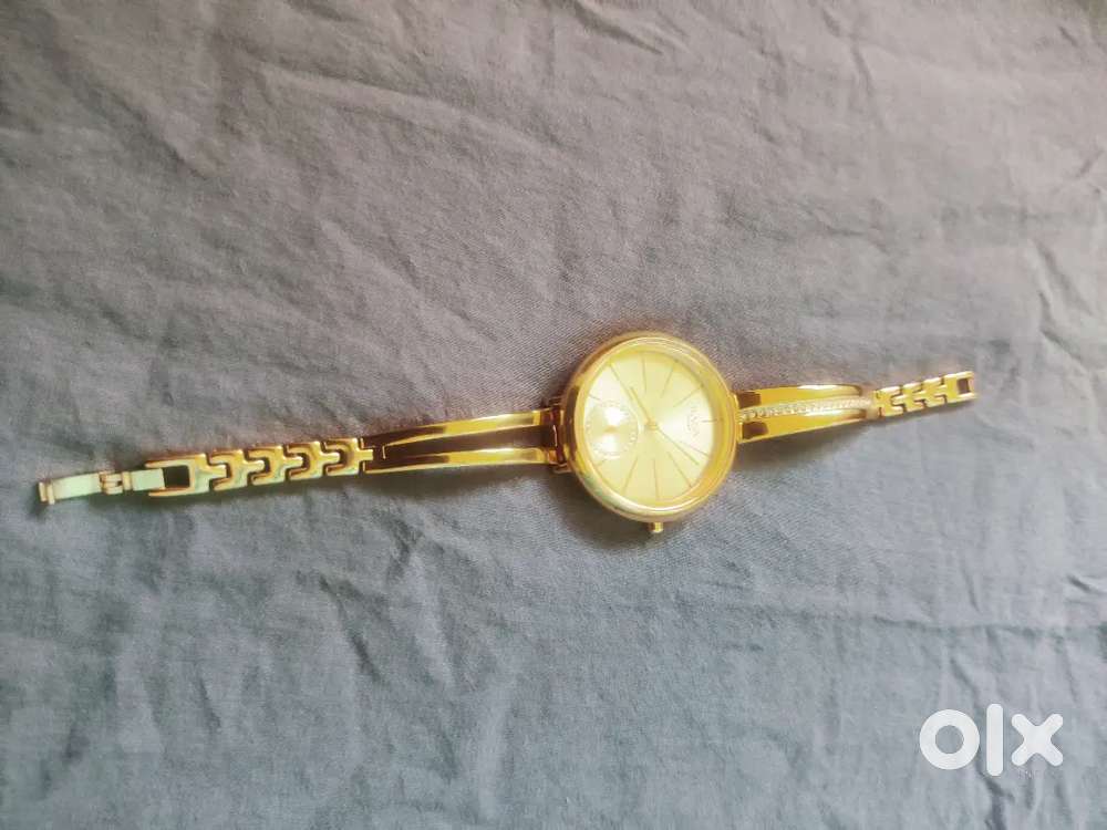 This is a gold tone titan raga women's analog watch with a metal