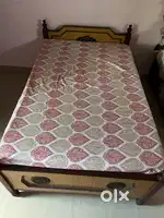 Cot with mattress and a wooden table with drawer