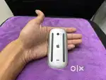 Apple Magic Mouse, likely the Magic Mouse 2, held in a hand. Key apple